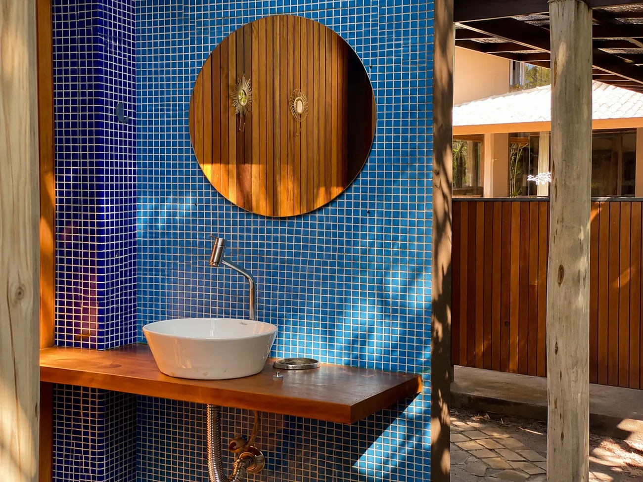 Ducha externa da Casa Paraíso revestida de mosaico azul, com cuba branca