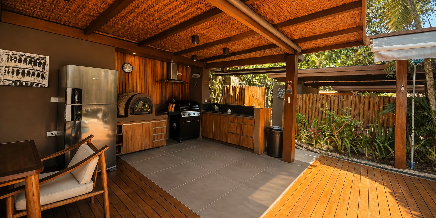 Espaço gourmet coberto da Casa Paraíso com forno, bancada, mesa e TV