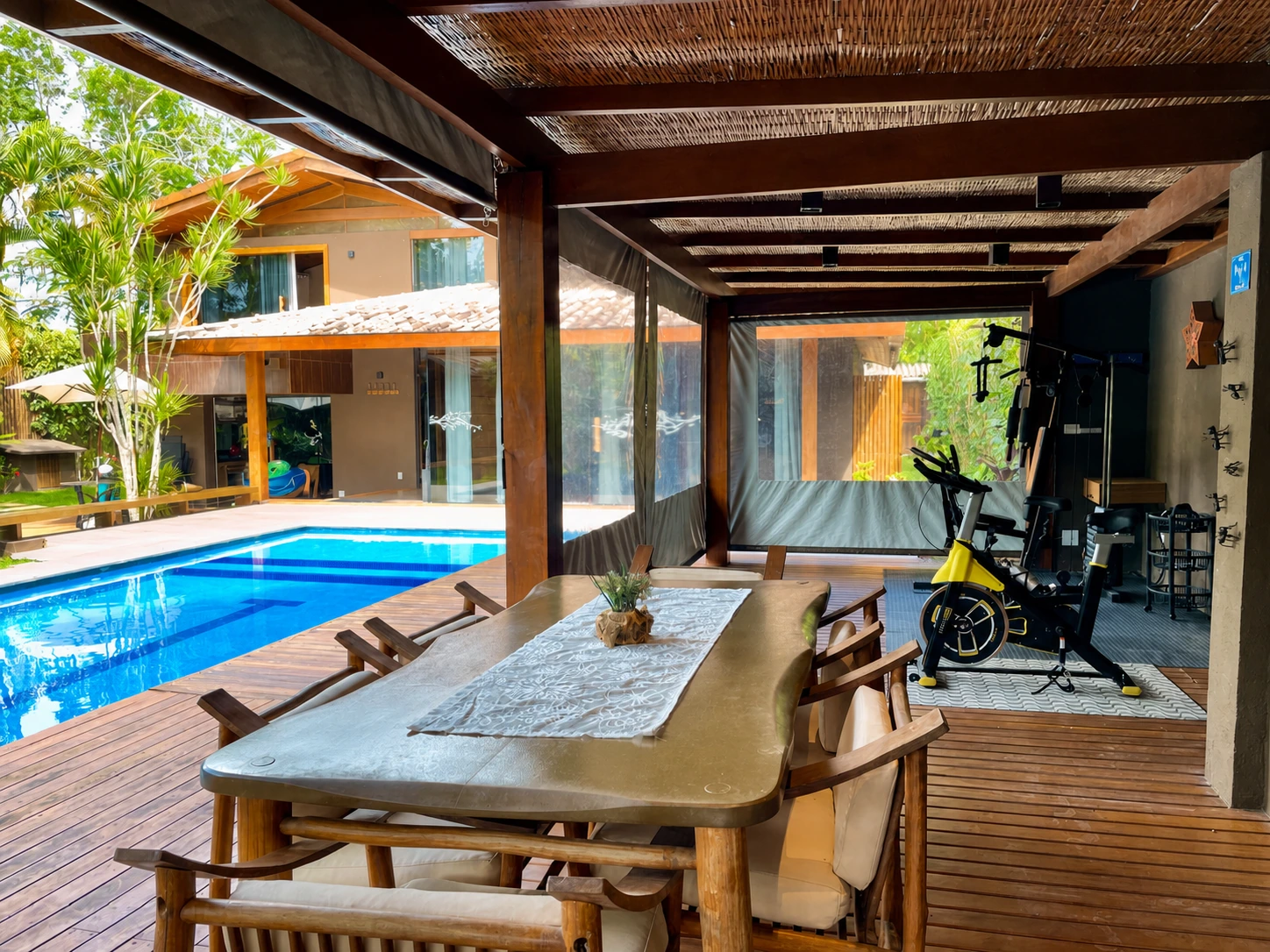 Área gourmet de Casa Paraíso abierta hacia la piscina, con mesa de comedor y mini gimnasio.