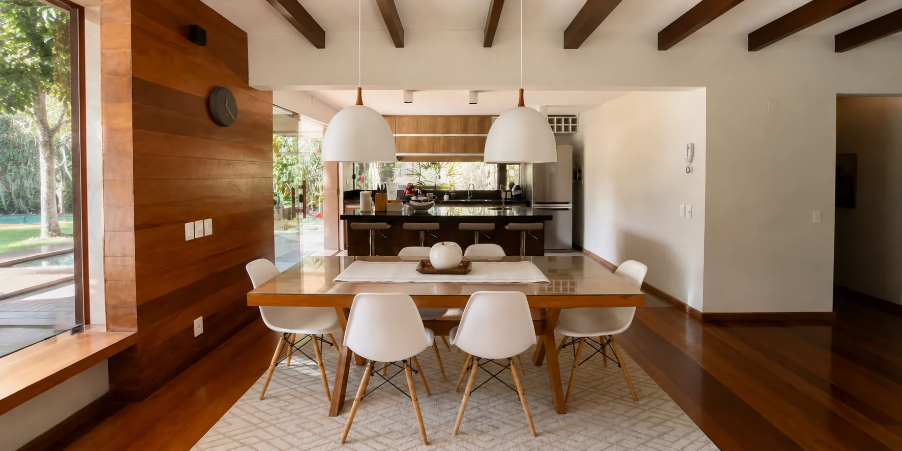 Sala de jantar da Casa Paraíso com mesa e cadeiras Eames sob o teto de madeira