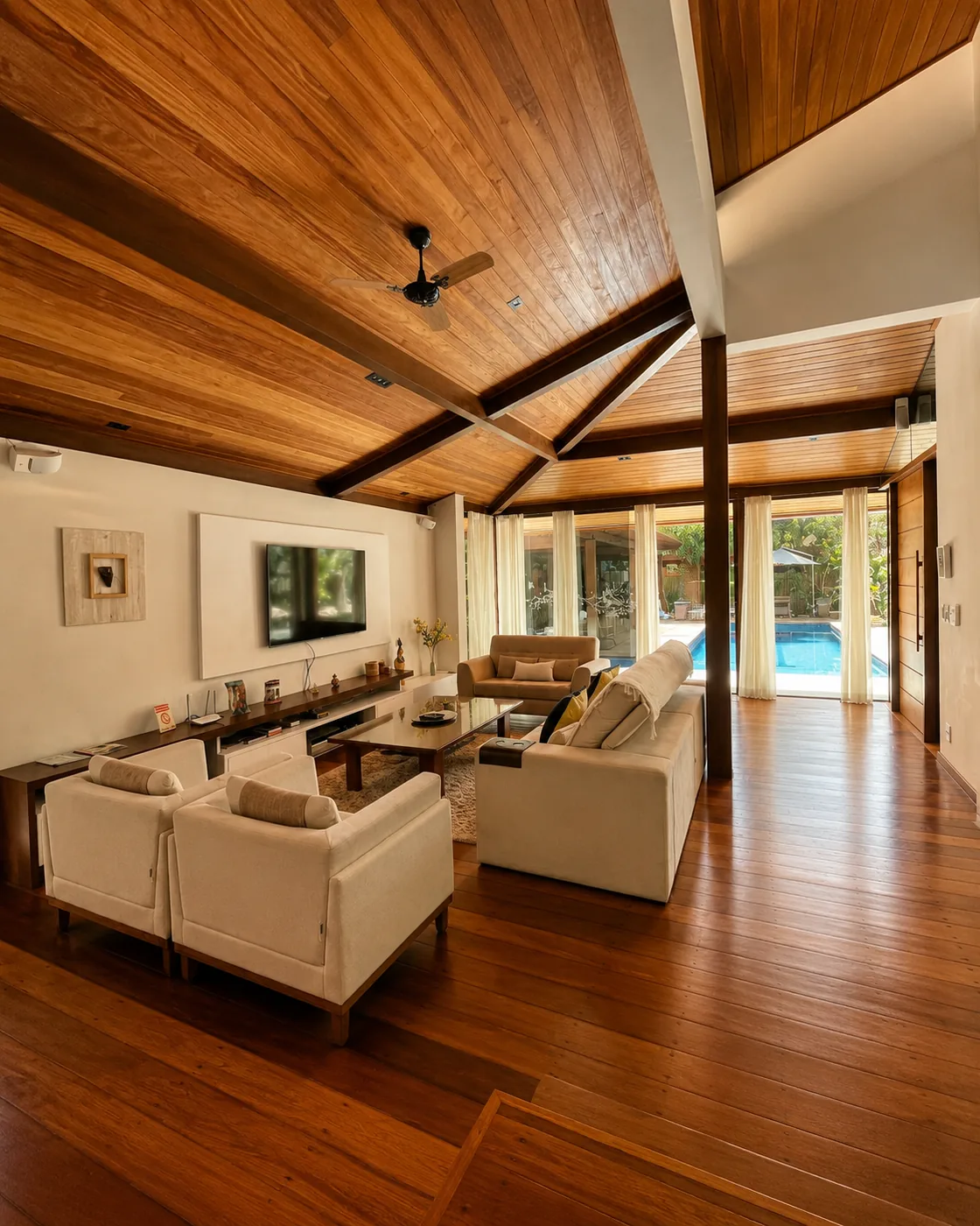 Sala de estar ampla da Casa Paraíso, com sofás claros e pé-direito alto de madeira