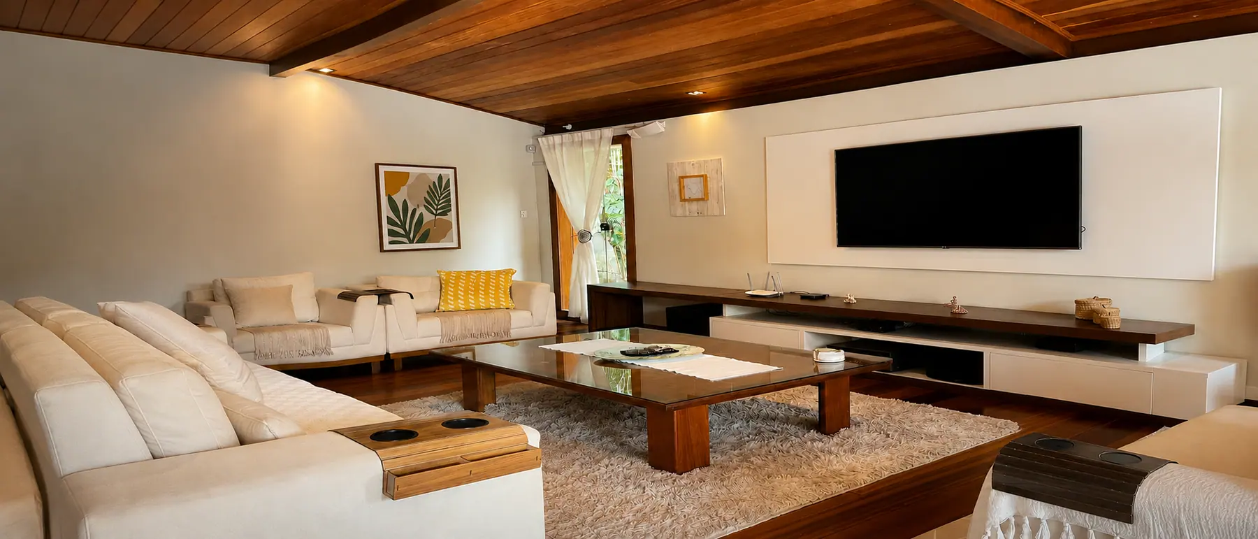 Ambiente integrado de estar da Casa Paraíso com sofá espaçoso e Smart TV