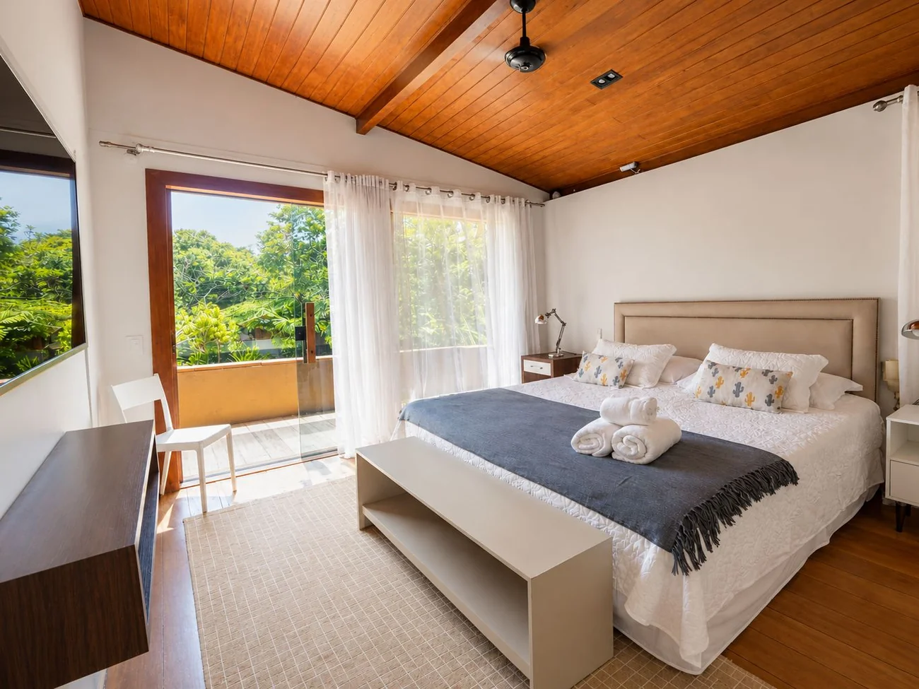 Suíte master da Casa Paraíso com varanda, janelas amplas e vista para o jardim