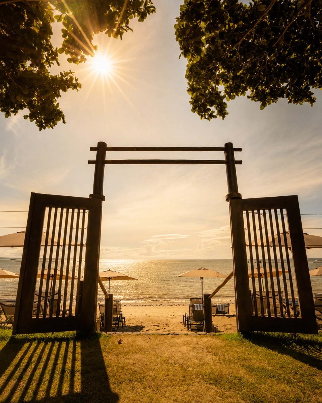 Wooden gateway on the sand at an Arraial d'Ajuda beach, with the sea in the background