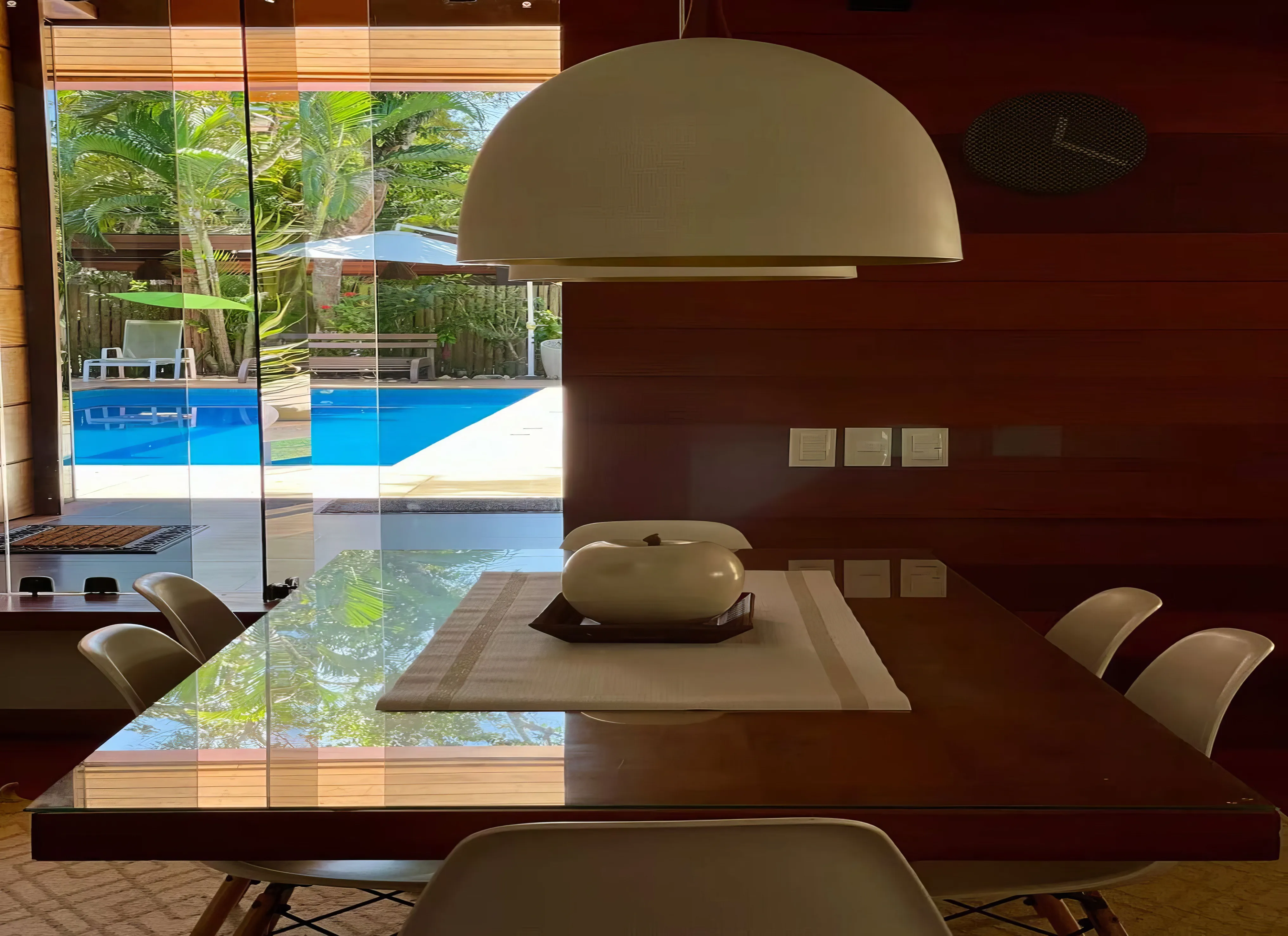 Área gourmet externa coberta com churrasqueira, forno e mesa de jantar.