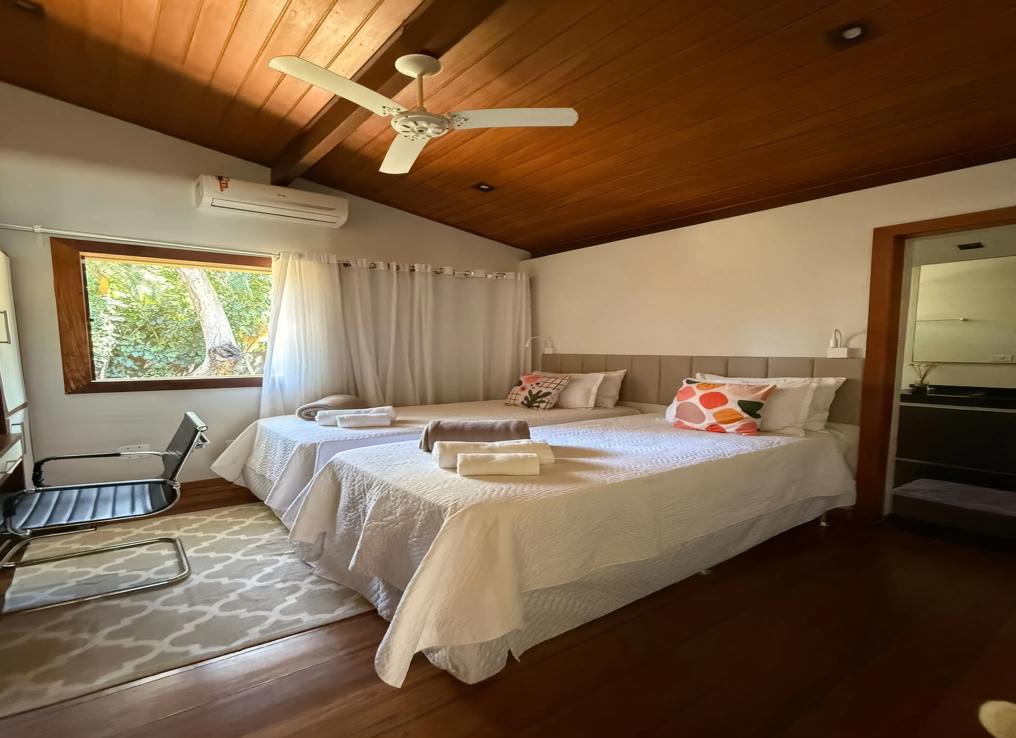 Sala de estar espaçosa com sofá confortável, TV de tela grande e vista para o jardim.